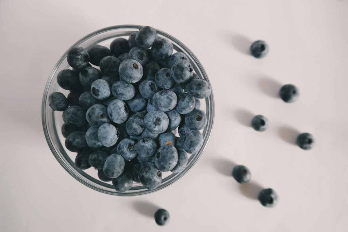 A top view of fresh blueberries spilling from a glass bowl on a white background, showcasing vibrant colors.